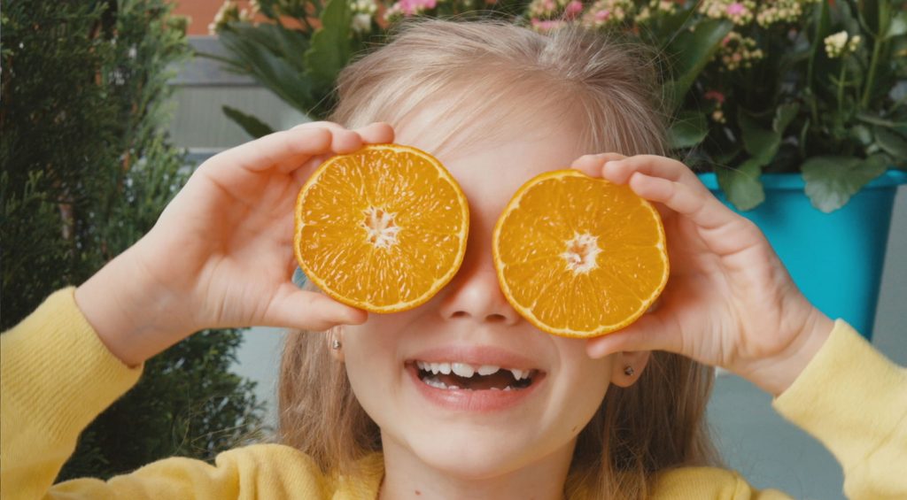 Girl holding orange slices in front of her eyes